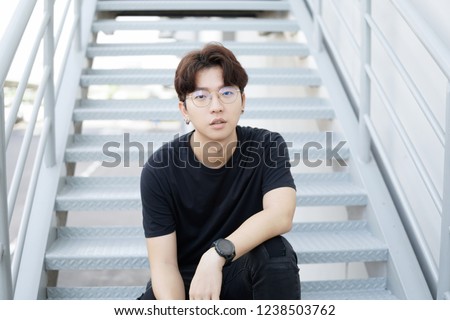Handsome asian CASUAL glasses man sit on a staircase and smile posing on gray background.
Portrait of young KOREAN against staircase background. Royalty-Free Stock Photo #1238503762