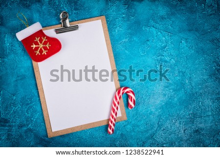 Top view of mockup composition with blank white sheet of paper and Christmas decoration as toy and candy on blue concrete background with copy space
