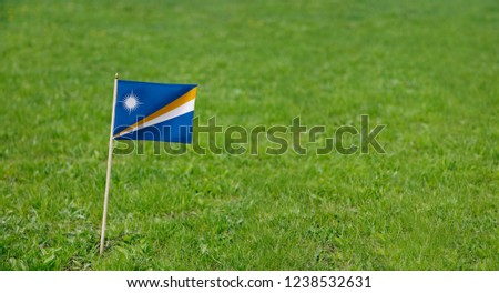 Marshall Islands flag. Photo of Marshall Islands flag on a green grass lawn background. Close up of national flag waving outdoors.