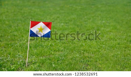Saba flag. Photo of Saba flag on a green grass lawn background. Close up of national flag waving outdoors.