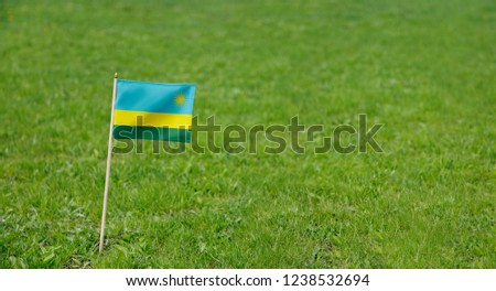 Rwanda flag. Photo of Rwanda flag on a green grass lawn background. Close up of national flag waving outdoors.