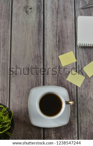 Wooden office desk table with a notebook, a handle, a cup of coffee and a flower pot. Top view with copy space.