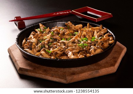 shimeji mushrooms in iron pan in a black background.