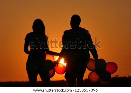 Happy couple playing in sunset with balloons.