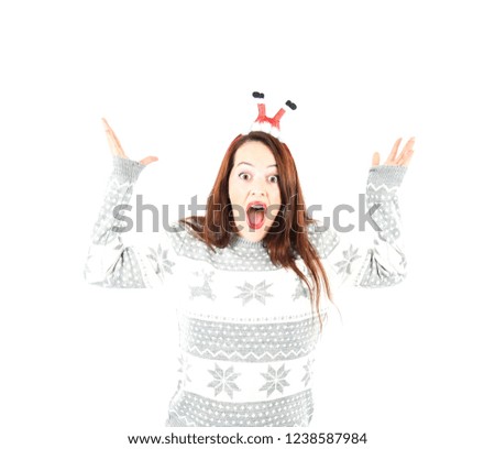 Amazed young woman  wearing a headband with Santa Claus legs and a Christmas jumper against a white background