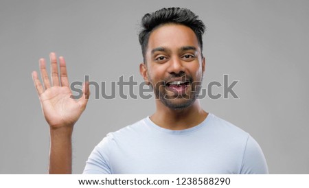 people, emotion and facial expression concept - happy smiling indian man waving hand over grey background Royalty-Free Stock Photo #1238588290
