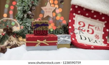 Christmas gifts or present boxes. Colorful lights, globes and decorations in the background, on rustic wooden surface. Christmas stocking with the "25th december" written on it