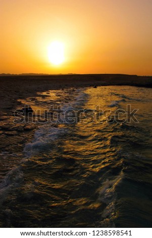 Orange sunset and waves on the ocean surface. Evening on the beach and tropical sea. Seascape photography.