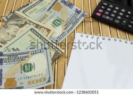 Closeup of money, calculator and notepad with copy space on wooden background. Finance and savings concept. Selective focus