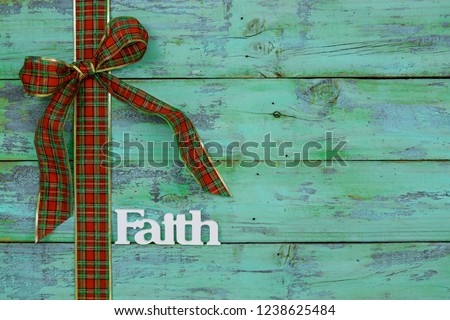 Blank rustic antique teal blue wood sign with red and green plaid Christmas bow border and the word FAITH; holiday background with aged painted copy space