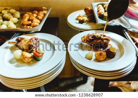 Waiters of a catering company plating the main course of a business lunch.