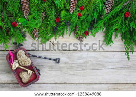 Blank wood sign with Christmas tree garland border with pine cones and red wagon with key and hearts; holiday background with copy space