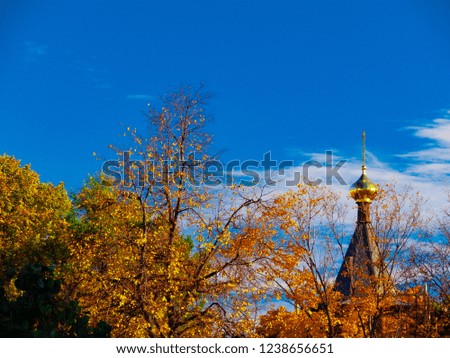 Orthodox church in autumn forest. Christian Russian temple through trees. Religion historical architecture. Golden dome on cloudy sky. Travel in fall season in Russia. Russian nature banner template. 