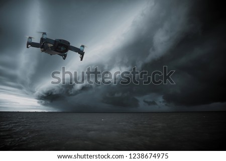 UAV drone copter flying with digital camera.Drone with high resolution digital camera. Flying camera take a photo and video.The drone with professional camera takes pictures of the rain storm on sea