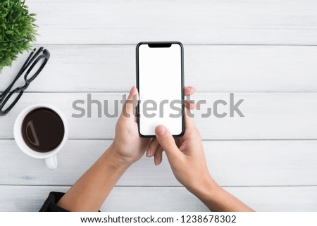 Hand using smartphone with blank screen on white wooden background, top view, copy space