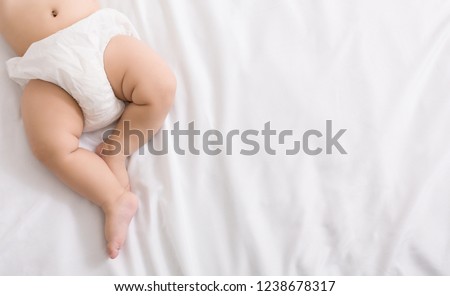 Newborn baby belly and legs in diaper, lying on white bed, top view, copy space Royalty-Free Stock Photo #1238678317