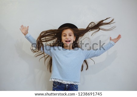 A child with her hands in hair. Positive photo session in the room.