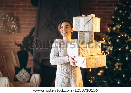 Woman with lots of presents in front of Christmas tree