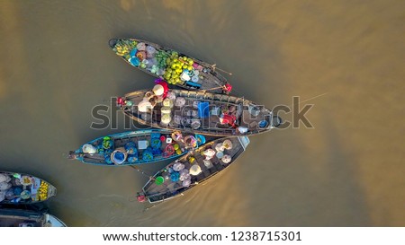 AERIAL, TOP DOWN: Flying away from bustling floating market on the tranquil river delta in the Vietnamese countryside. Local people offering their produce from their wooden boats on a sunny evening.
