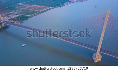 DRONE: Flying above a busy concrete suspension bridge crossing the murky river in sunny Vietnam. Countless vehicles drive up and down the freeway and cross the large murky river. Amazing architecture