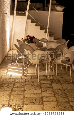 Outdoor space of a resort with chairs and tables for guests and floor lighting.