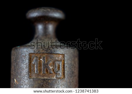 A kilogram weight used for weighing a given quantity in the store. Weights of one kilogram and two kilograms. Dark background. Royalty-Free Stock Photo #1238741383