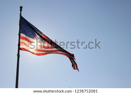 Large American flag with the sun behind shining through.