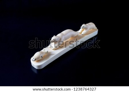 Seal escaping from polar bears, walrus bone figurines on a black background