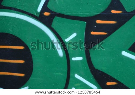Fragment of graffiti drawings. The old wall decorated with paint stains in the style of street art culture. Colored background texture in green tones