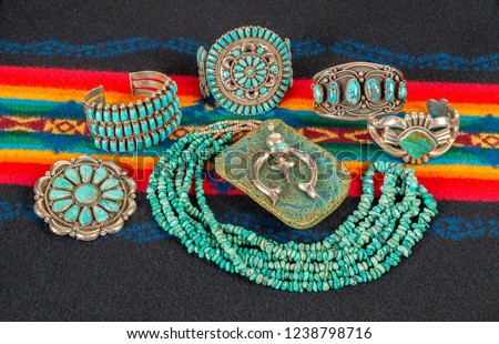 Collection of Native American Jewelry on a Colorful Textile Background. Turquoise and Sterling Silver Necklace, Bracelets and Pendants.