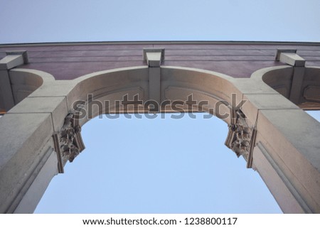 Upward view of historic arches at Portland Saturday Market against a light blue autumn sky.