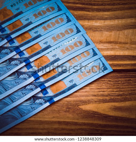 Dollars in a row diagonally on wooden boards. Dark blue light, vignetting.