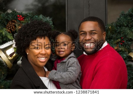 African American Family playing and laughing with their daughter.