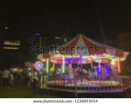 abstract blur image of kid play carousel in night festival for background usage , vintage