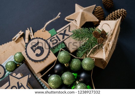 Advent calendar with gift bags and boxes filled with candy. Christmas decor. Gift wrapping Kraft paper. Black background.