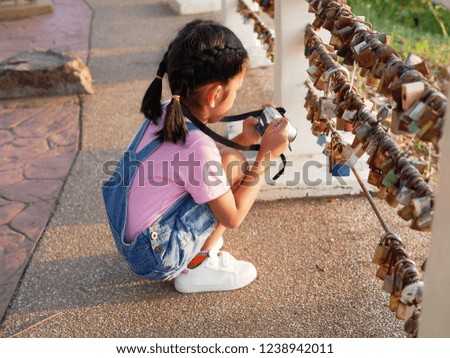 A little girl holding camera with taking a picture. Asian kid making photo travelling.