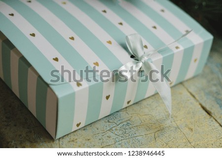 Christmas gift box on golden background. Striped Present near Christmas tree. Close up. Copy space