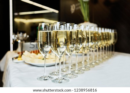 rows of champagne and sparkling wine glasses at night time party new year corporate party concept
