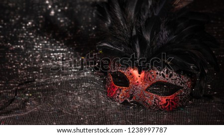 Carnival time. Venetian mask, red with feathers, on black shiny background, copy space