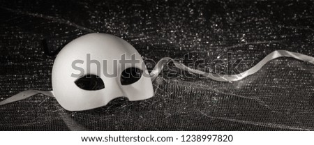 White carnival mask, half face on black shiny background, closeup view, banner