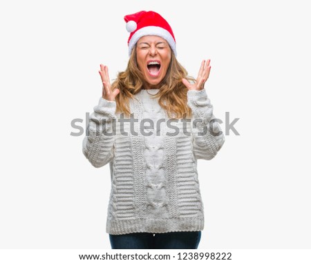 Middle age senior hispanic woman wearing christmas hat over isolated background celebrating mad and crazy for success with arms raised and closed eyes screaming excited. Winner concept