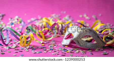 Carnival party. White silver mask, streamers and confetti on bright pink background, banner