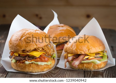 Homemade cheese burgers or hamburgers on brown paper put on wood table with copy space. Fast food for breakfast or lunch.