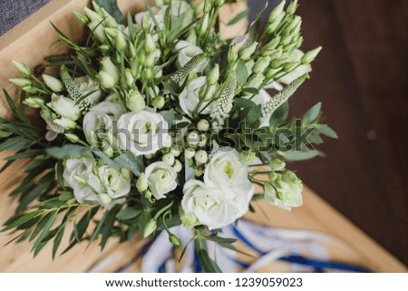 Wedding bouquet of white, green flowers with blue ribbons and decor. The bride's bouquet. Stylish bouquet on a wooden background