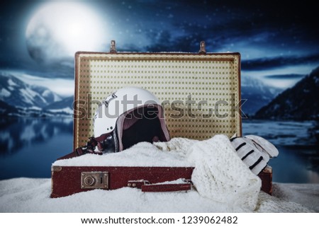 Retro suitcase in snow and winter landscape of lake with moon 