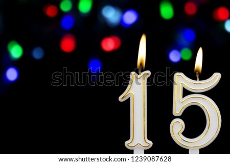 Birthday candles  on black background with defocused colofrul lights, number 15