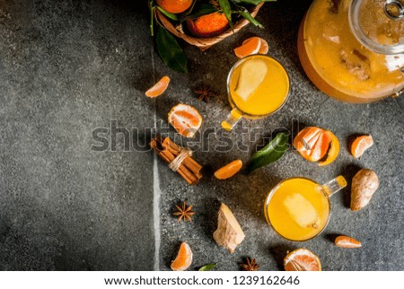 Tangerine Ginger Tea with cinnamon and anise, with ingredients, on dark stone background, copy space top view