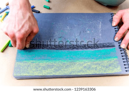 hands holding chalks and drawing on a blackboard