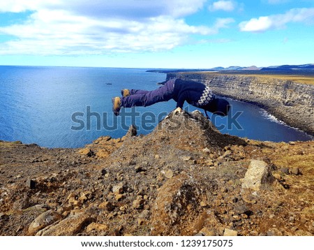 Young strong man practicing yoga, standing in flexible pose on hands on Stone, making balance exercise,