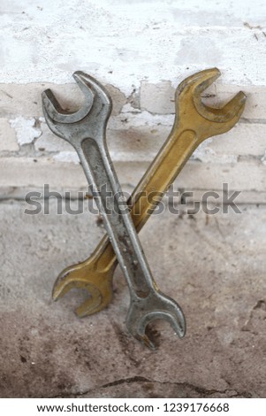 Steel and golden old retro wrench near the brick wall